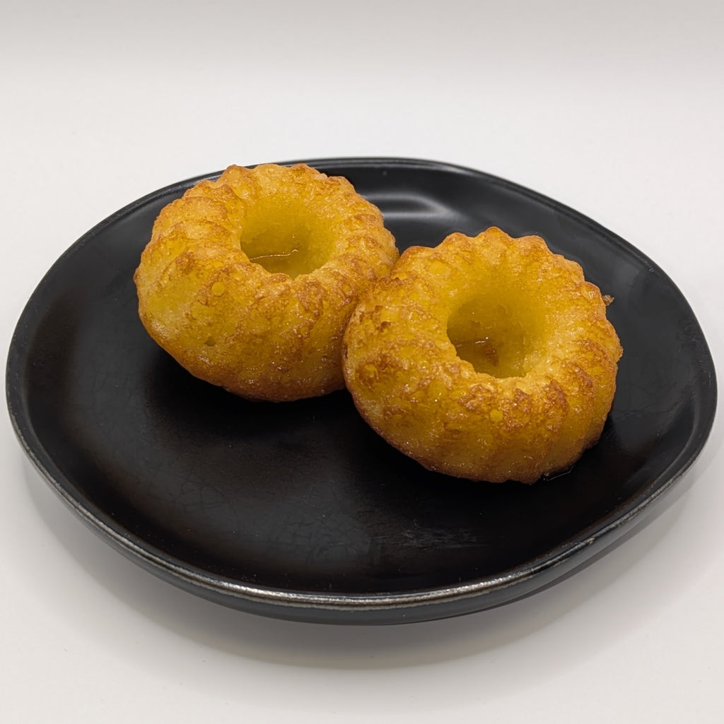 Two medium peach bellini cakes sitting on a black plate