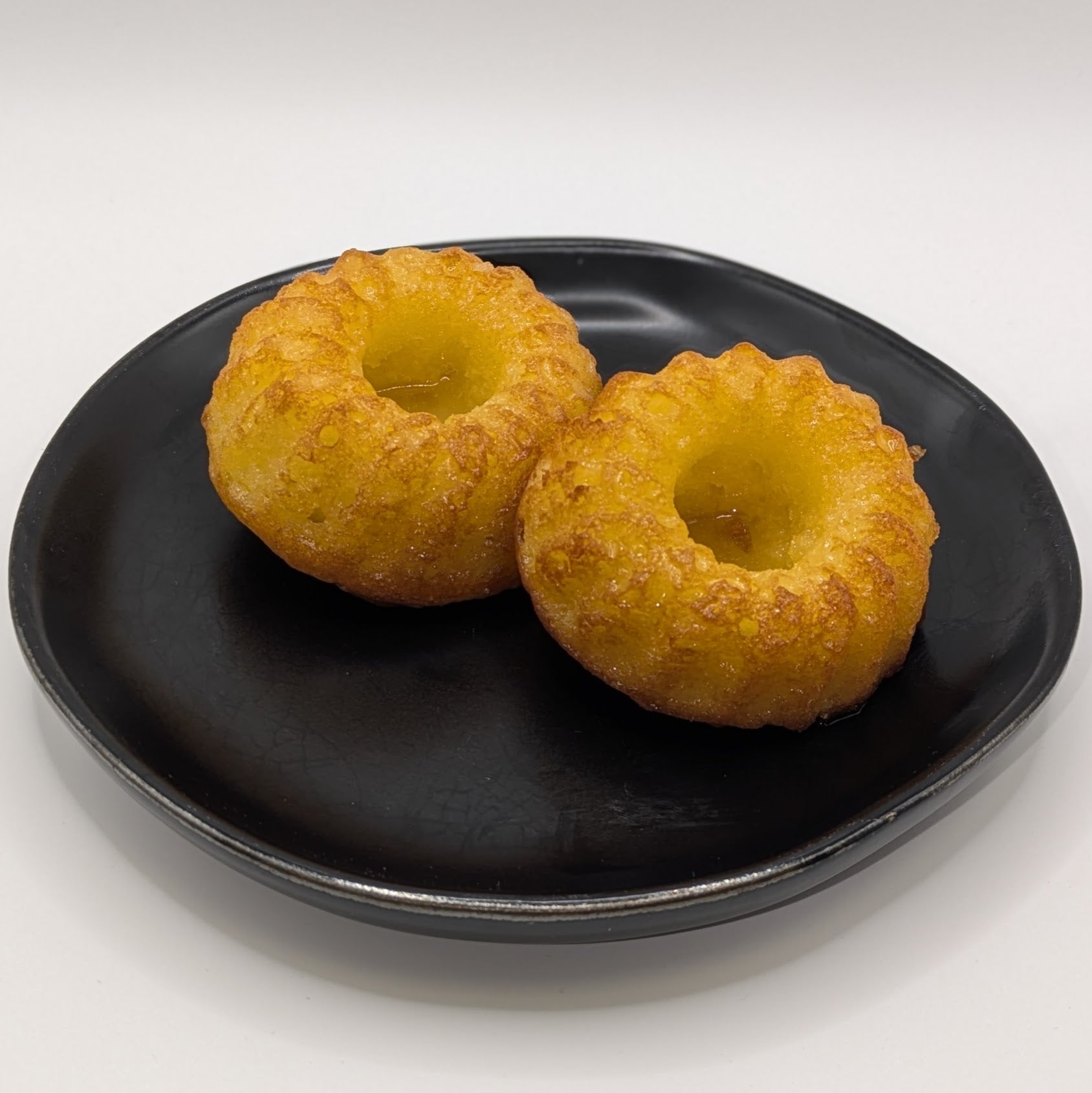 Two medium peach bellini cakes sitting on a black plate