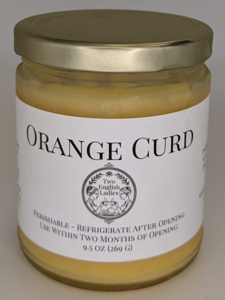 Jar of orange curd with a gold lid on a white background