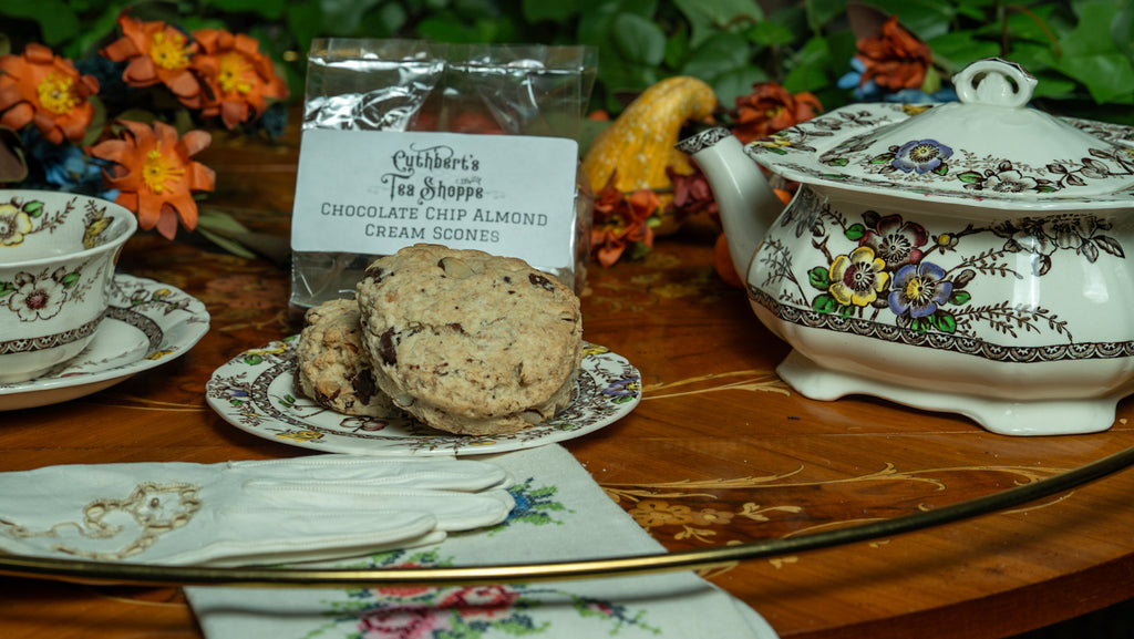Chocolate chip almond cream scones on a decorative plate with a tea set in the background