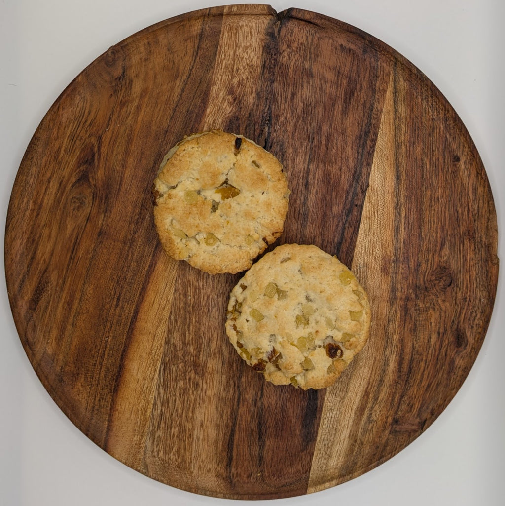 Two apricot ginger scones on a wooden cutting board with a white background